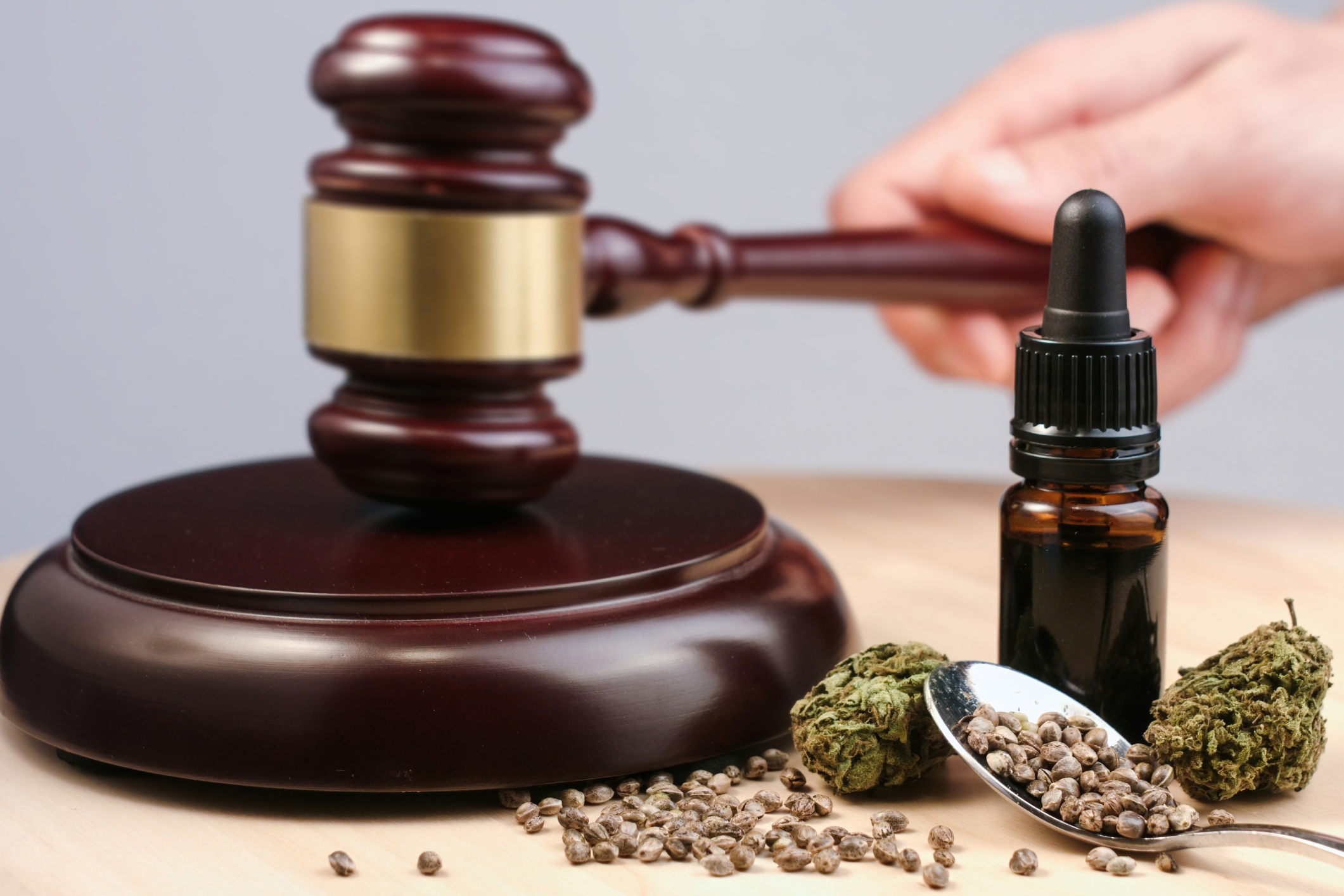A gavel, cannabis buds, and oil bottle on a wooden surface.