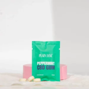 A green packet of Peppermint CBD Gum on a pink platform with a white background.