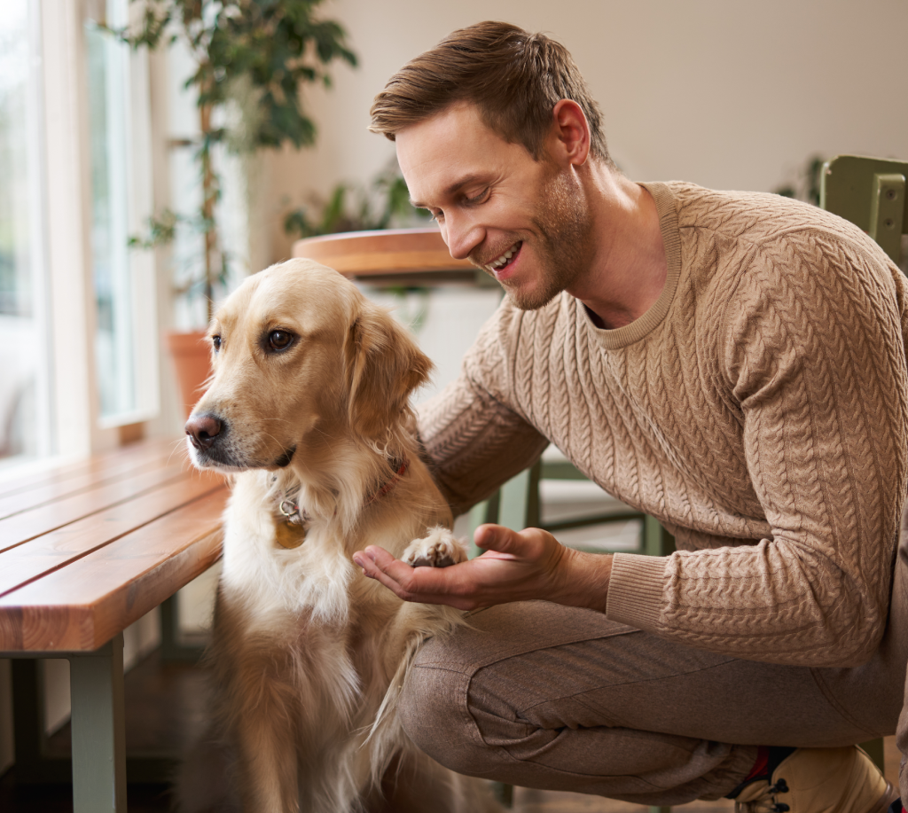 Man happily petting a golden retriever indoors.